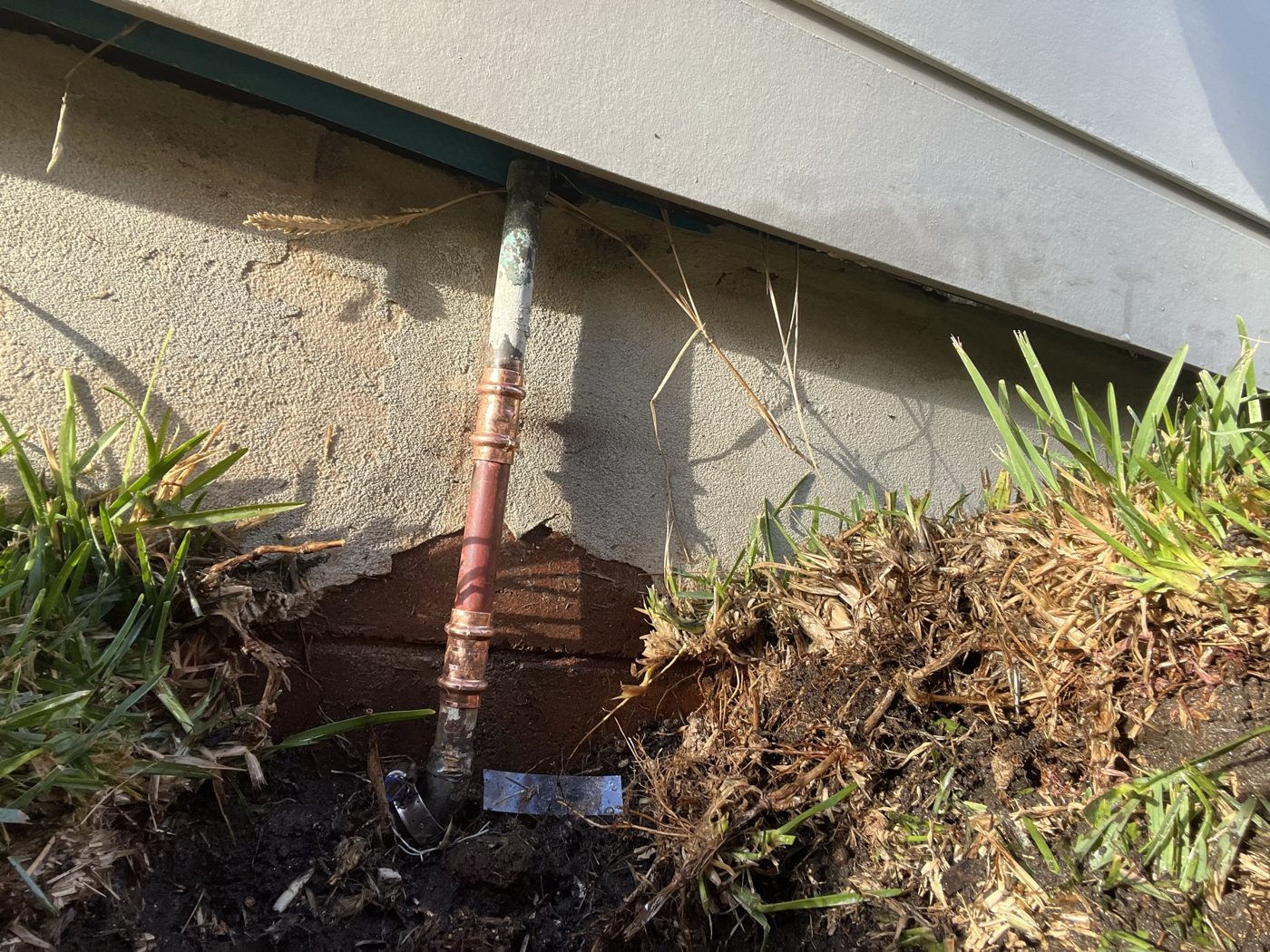 Repaired copper water pipe on a house wall after a burst